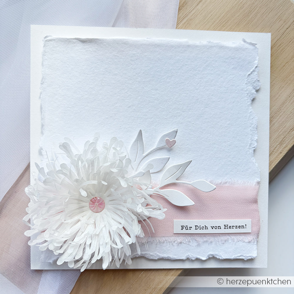 Handgefertigte Karte mit einer weißen Papierblume, einem rosa Band und dem Schriftzug „Für Dich von Herzen!“ auf fein strukturiertem, handgeschöpftem Büttenpapier. Perfekt als Hochzeitseinladungskarte oder um einer Karte eine besondere Note zu verleihen – verziert mit zarten Fotostickereien für einen eleganten Abschluss.