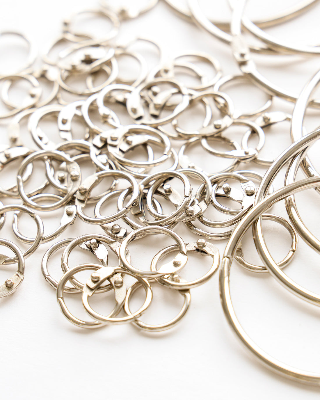 Ein Stapel silberner Ordnerringe und Schlüsselanhänger, die auf einer weißen Fläche verstreut sind.