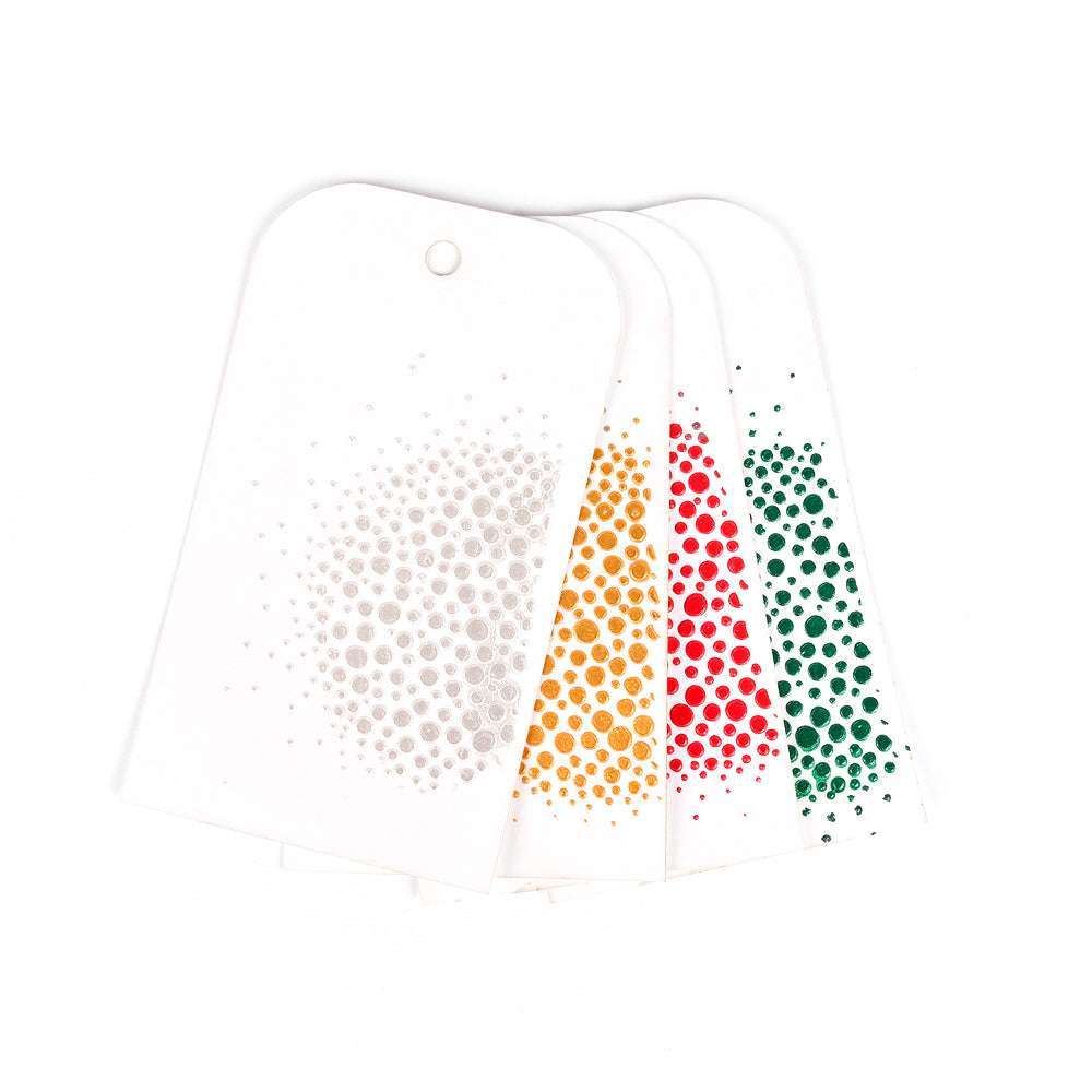 Vier weiße Anhänger von The Crafters Workshop mit farbigen Punktmustern in Grau, Orange, Rot und Grün sind auf einem weißen Hintergrund aufgefächert - ideal für Mixed Media-Techniken wie Modellierpaste oder Stencil Butter.