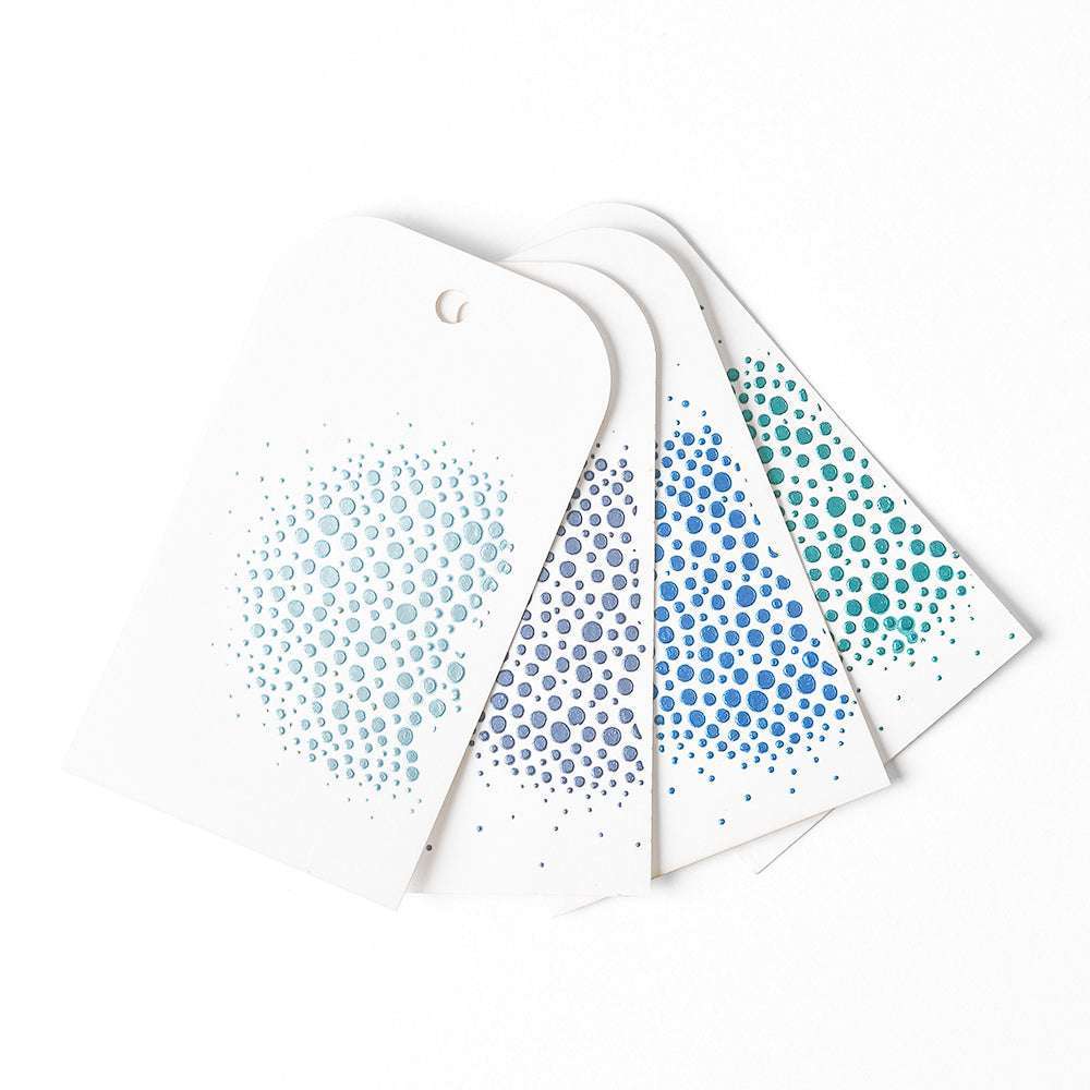 Vier weiße Karten mit abgerundeten Ecken von The Crafters Workshop, die jeweils mit blauen und grünen Punkt-Clustern verziert sind - ideal für Mixed-Media-Experimente oder zum Hinzufügen von Highlights mit Stencil Butter.