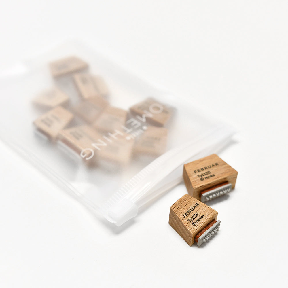 Kleines Holzstempel-Set von Alexandra Renke: Hochwertige Stempel mit Monats- und Tagesmotiven, einige in transparenter Tasche, zwei im Fokus. Perfekt zum kreativen Gestalten von Kalendern oder Planern.