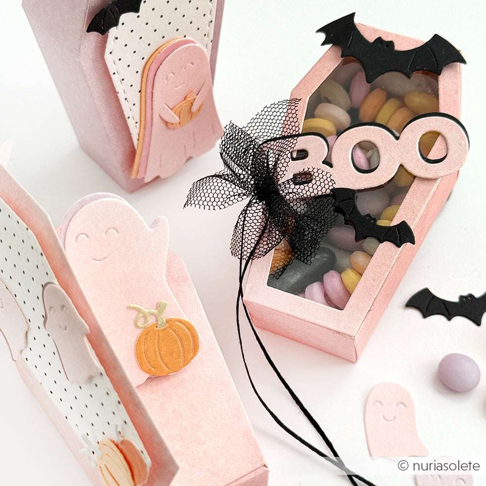 Die rosafarbenen Halloween-Süßigkeitenboxen von Alexandra Renke in Form von Särgen und Gespenstern mit Fledermaus- und "Buh"-Details sind mit Süßigkeiten gefüllt - ideal, um Ihrer festlichen Sammlung gruselige Inspirationen hinzuzufügen.