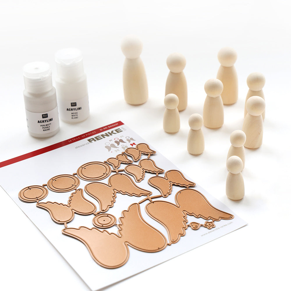 Alexandra Renke Holzklammerpuppen, Acrylfarbenflaschen und Engelsflügel Stanzen für festliche Weihnachtsdekoration sind ordentlich auf einer weißen Fläche angeordnet.