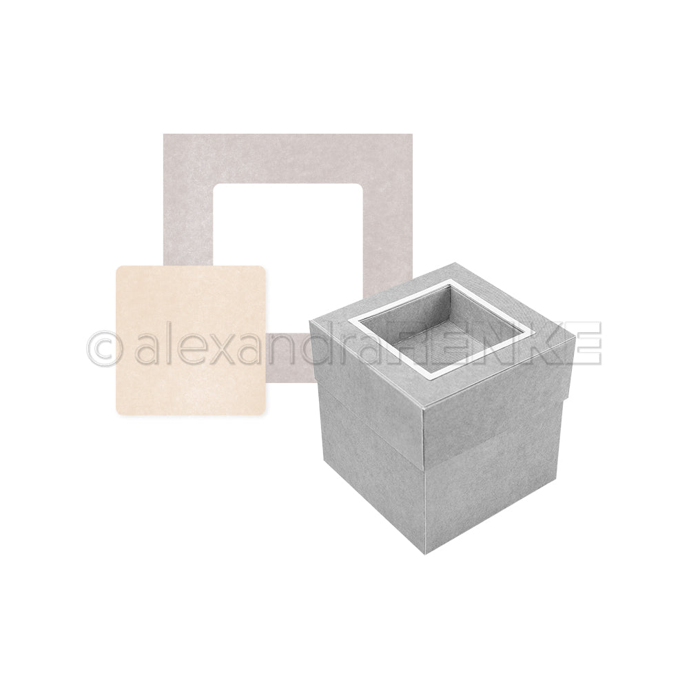 Eine quadratische graue Box mit offener Oberseite steht neben beigefarbenen und grauen flachen quadratischen Rahmen - ein stilvolles Alexandra Renke-Paket zur Unterstützung der Kreativität.
