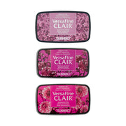 Drei Tsukineko VersaFine Clair Pigment-Tinte Stempelkissen in verschiedenen Rosatönen mit floralen Motiven auf den Deckeln - ideal zum detailreichen Stempeln.