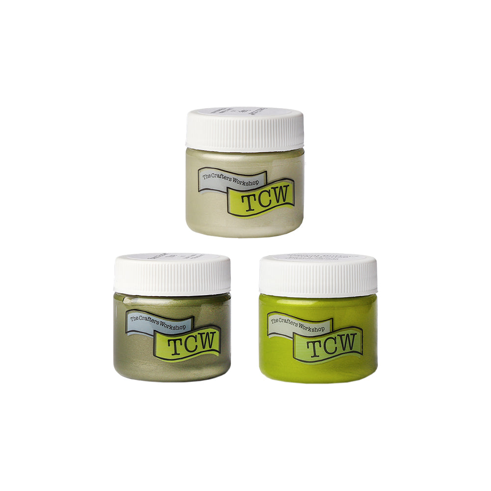 Drei kleine Gläschen mit weißen Deckeln, beschriftet mit The Crafters Workshop, enthalten verschiedene Schattierungen von grünem Stencil Butter Gelmedium - ideal für Schablonen und andere Mixed Media Projekte.