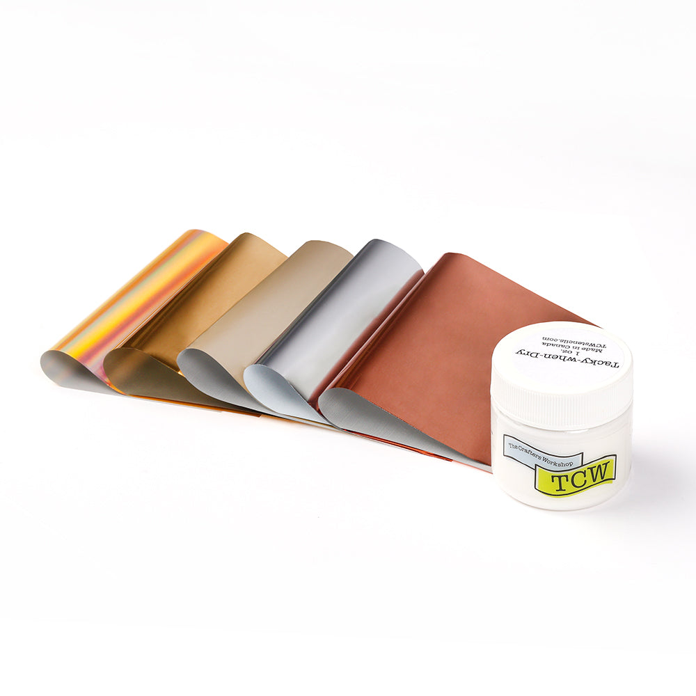 Fünf Metallic-Bögen in verschiedenen Farben neben einem weißen alexandrarenke Glas - ideal für kreative Papierbasteleien oder in Kombination mit Tacky when Dry für beeindruckende Folienverzierungseffekte.