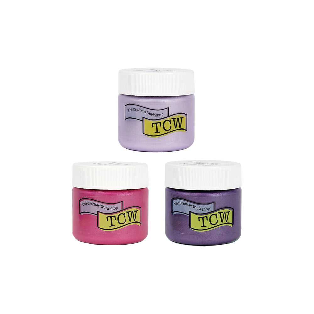Drei Gläser mit „TCW Stencil Butter“-Farbe in den Farben Rosa, Lavendel und Violett mit weißen Deckeln sind in Dreiecksform angeordnet – ideal, um Ihren Mixed-Media-Projekten lebendige Farben und Struktur zu verleihen.