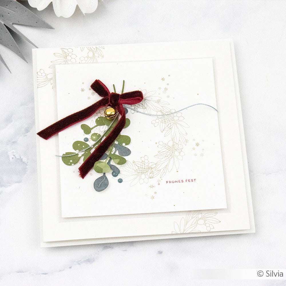Quadratische Weihnachtskarte von Alexandra Renke mit floralem Design, roter Samtschleife, Glöckchen und dem Text "Frohes Fest". Hochwertige Karte mit besonderer Papierhaptik; passende Umschläge runden den festlichen Look ab.