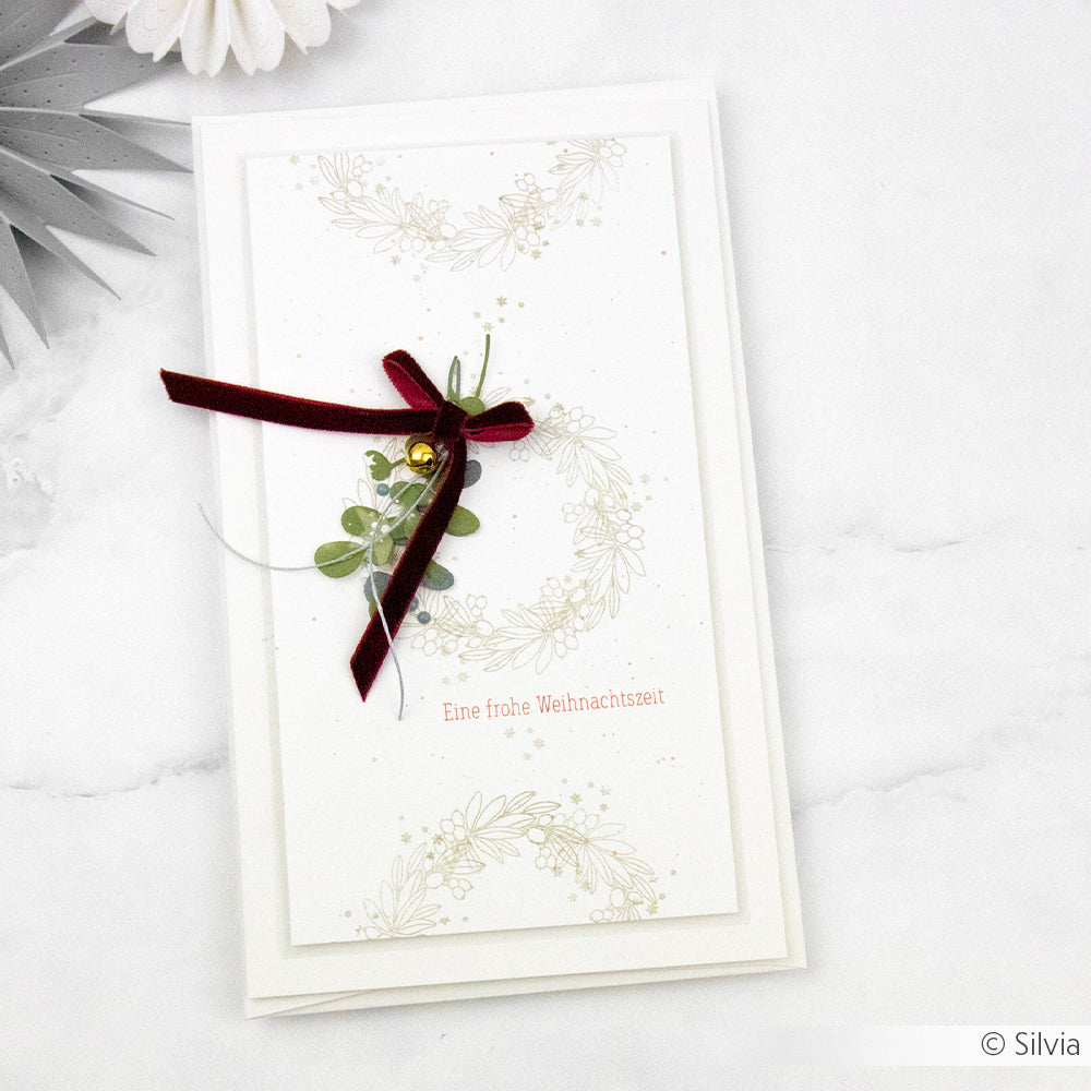 Weiße Weihnachtskarte mit Kranzmotiv, rotem Band und dem Schriftzug „Eine frohe Weihnachtszeit“ auf Marmorhintergrund – perfekt für Ihre Hauskollektion und ideal für Umschläge und Karten im Digitaldruck geeignet.