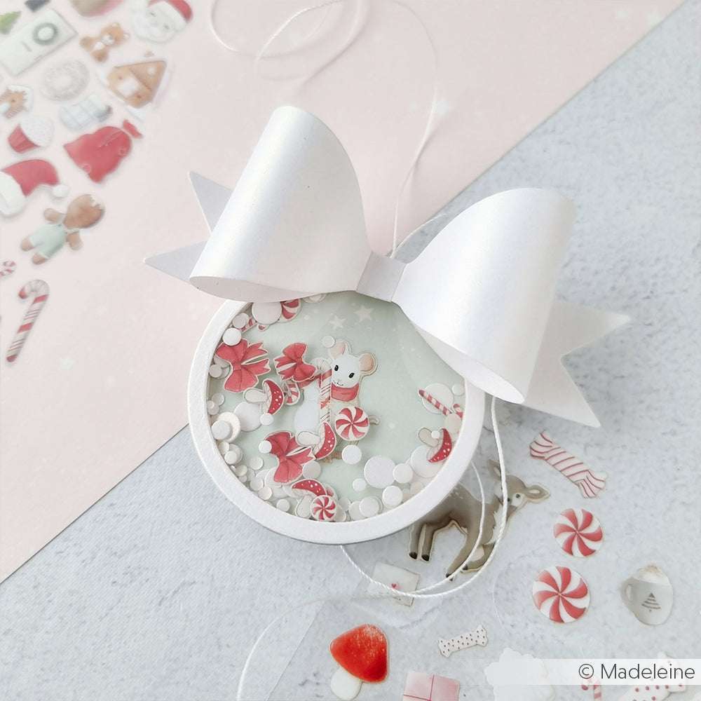 Rundes Weihnachtsornament von Alexandra Renke mit einer niedlichen Maus, Süßigkeiten und einer großen weißen Schleife - perfekt für festliche Sammlungen oder Weihnachtspakete. Umgeben von Dekorationen, die die Kreativität anregen.