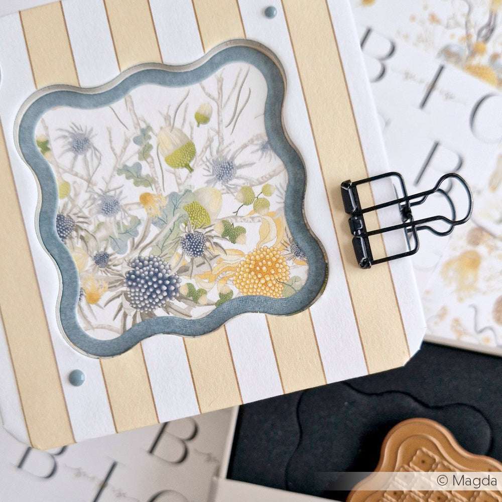 Eine dekorative Karte von Alexandra Renke mit einem floralen Design, einer schwarzen Büroklammer und einem creme-weiß gestreiften Hintergrund - perfekt, um die Kreativität in Ihren Projekten zu präsentieren oder Ihre persönliche Sammlung zu ergänzen.