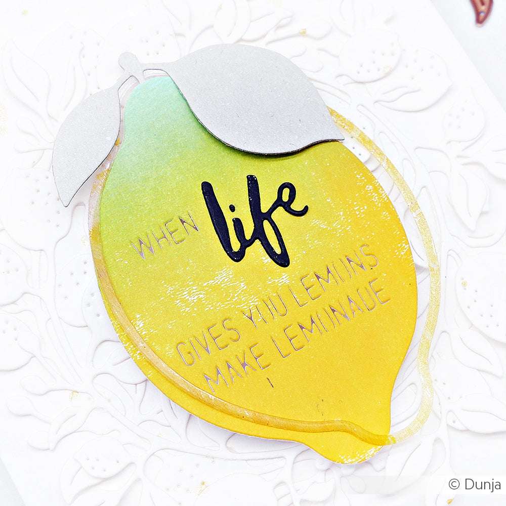 Eine Karte in Zitronenform von Alexandra Renke, die mit Designpapieren und Stanzen gestaltet wurde, zeigt "Wenn das Leben dir Zitronen gibt, mach Limonade" auf einem weißen, strukturierten Hintergrund.