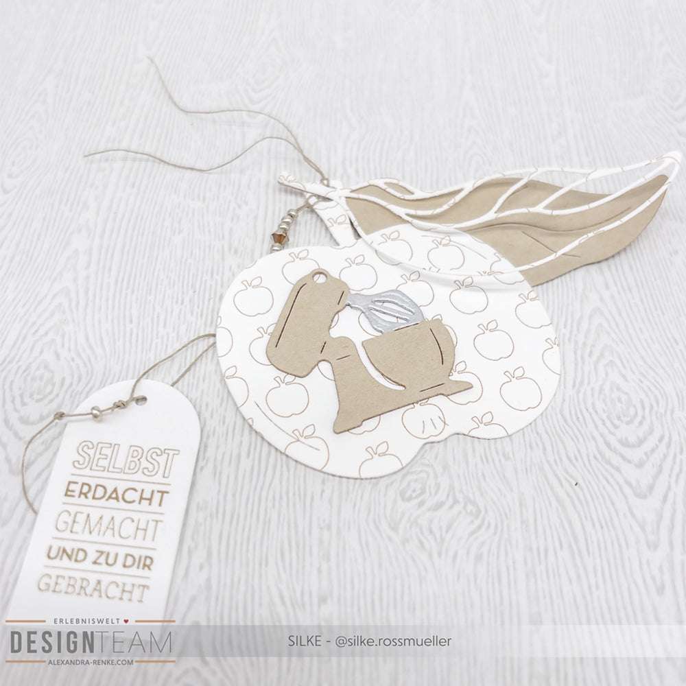 Handgefertigte Karte von Alexandra Renke mit einem beigen Hasen auf einem apfelförmigen Hintergrund, detaillierten Designpapieren, Blattausschnitten und einem deutschen Textanhänger, der mit der Motivstanze Apfel Etikett hergestellt wurde.