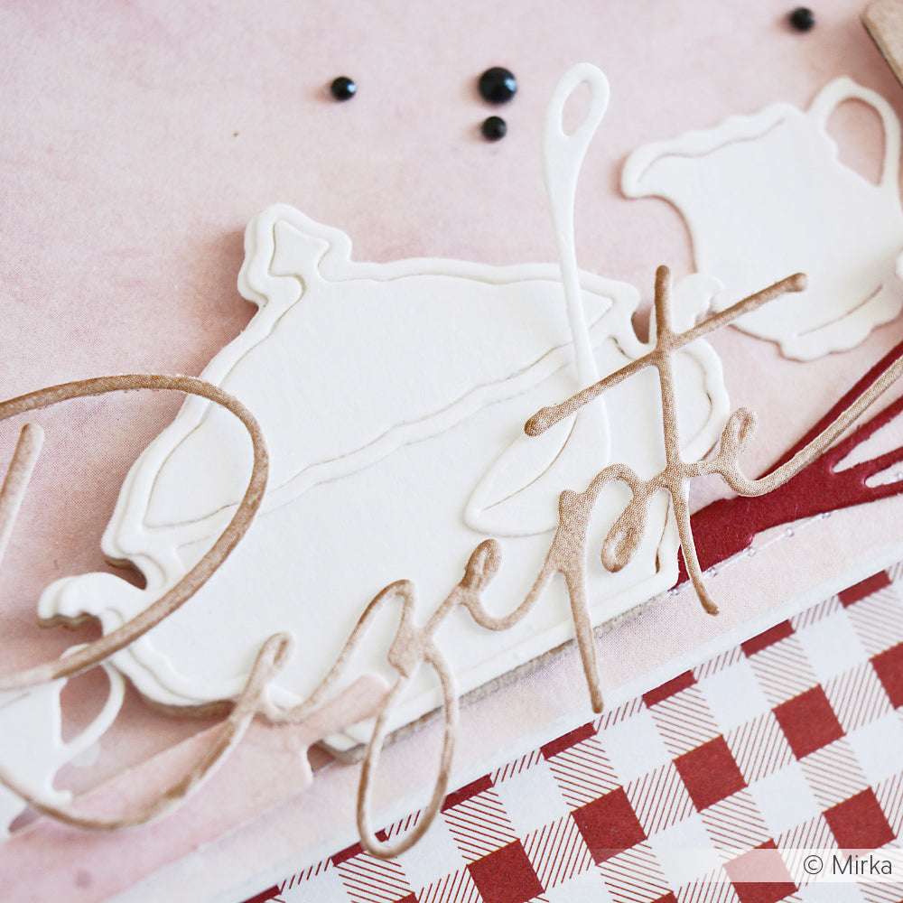 Nahaufnahme einer Papierbastelei mit der Alexandra Renke Motivstanze, die eine Teekanne, eine Tasse und den Text "Rezepte" auf einem Hintergrund aus kariertem Tischtuch zeigt.