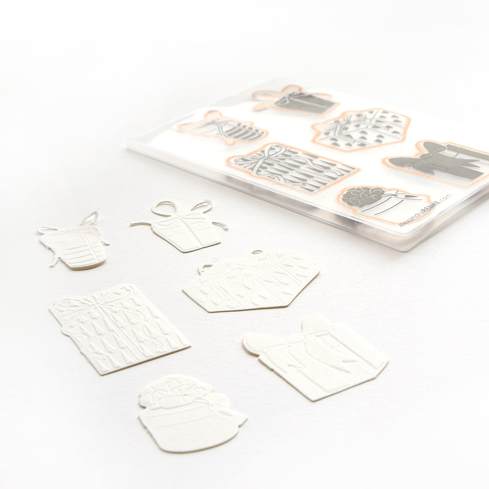 Verschiedene Geschenkausschnitte aus weißem Papier von Alexandra Renke mit einem passenden Aufkleberbogen, alle auf weißem Hintergrund.