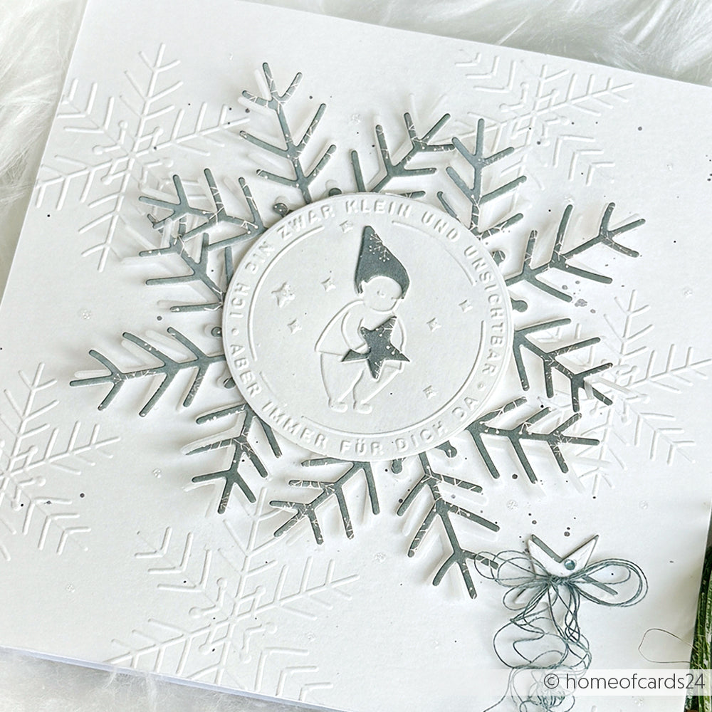 Weiße Weihnachtskarte von Alexandra Renke mit geprägten Schneeflocken, einer silbernen Schneeflocke und einem kreisrunden Elfenmotiv - hergestellt mit dem Cut & Emboss Folder für komplizierte Details, inspiriert von klassischen Wichtelgrüßen.