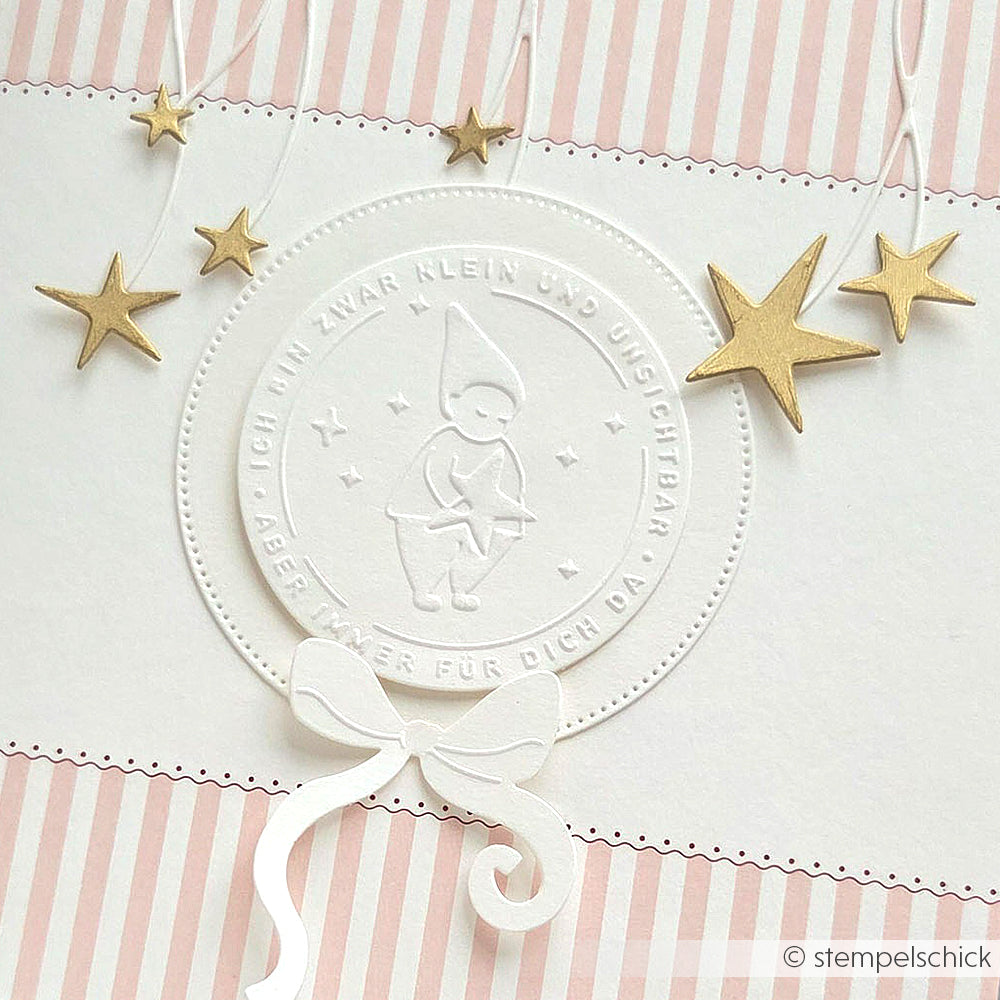 Geprägte Karte von Alexandra Renke, hergestellt mit einem Cut & Emboss Folder. Mit einer kleinen Elfe, goldenen Sternen und einer weißen Papierschleife auf rosa und weißen Streifen - ideal für Wichtelgrüße mit Ihren Lieblings-Stanzsystemen.