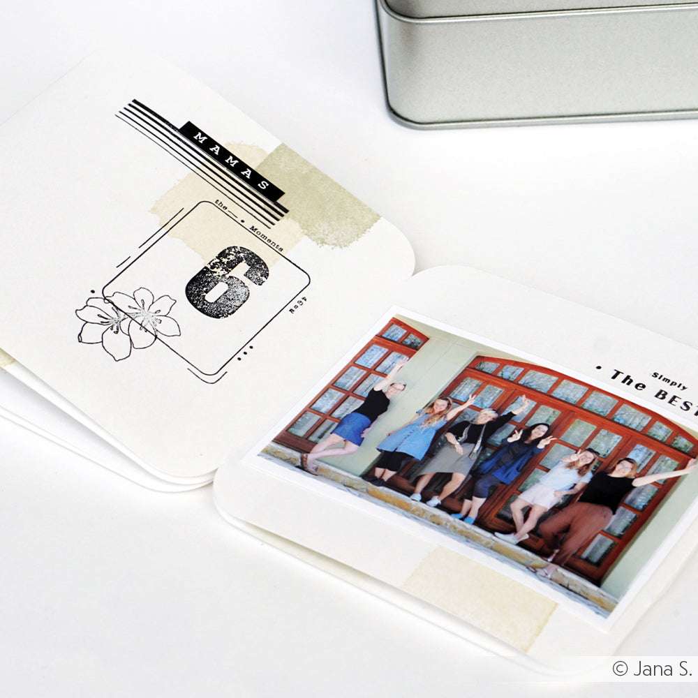 Aufgeschlagenes Scrapbook mit dem Schriftzug "MAMAS 6" auf einer Seite und einem Gruppenfoto von sechs springenden Frauen auf der anderen Seite, wunderschön verziert mit einzigartigen klaren Stempelmotiven von Alexandra Renke. Feiern Sie Freundschaft und schöne Erinnerungen weltweit.