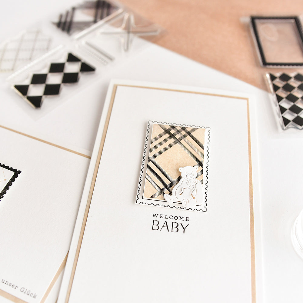 Eine handgefertigte "Welcome Baby"-Karte von Alexandra Renke, hergestellt auf weißem Cardstock mit einem karierten Photopolymer-Stempel und einem kleinen Bärendesign, veredelt mit einer rechteckigen Briefmarke als Akzent.