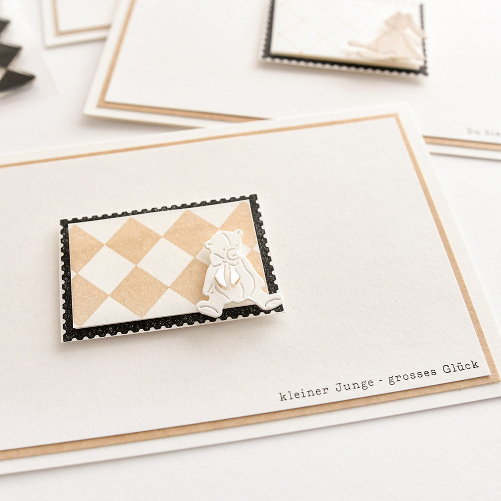 Eine handgefertigte Karte von Alexandra Renke mit einem ausgeschnittenen Bären auf einem karierten Rechteck und dem deutschen Text "kleiner Junge - großes Glück", hergestellt mit hochwertigen Photopolymer-Klarsichtstempeln.