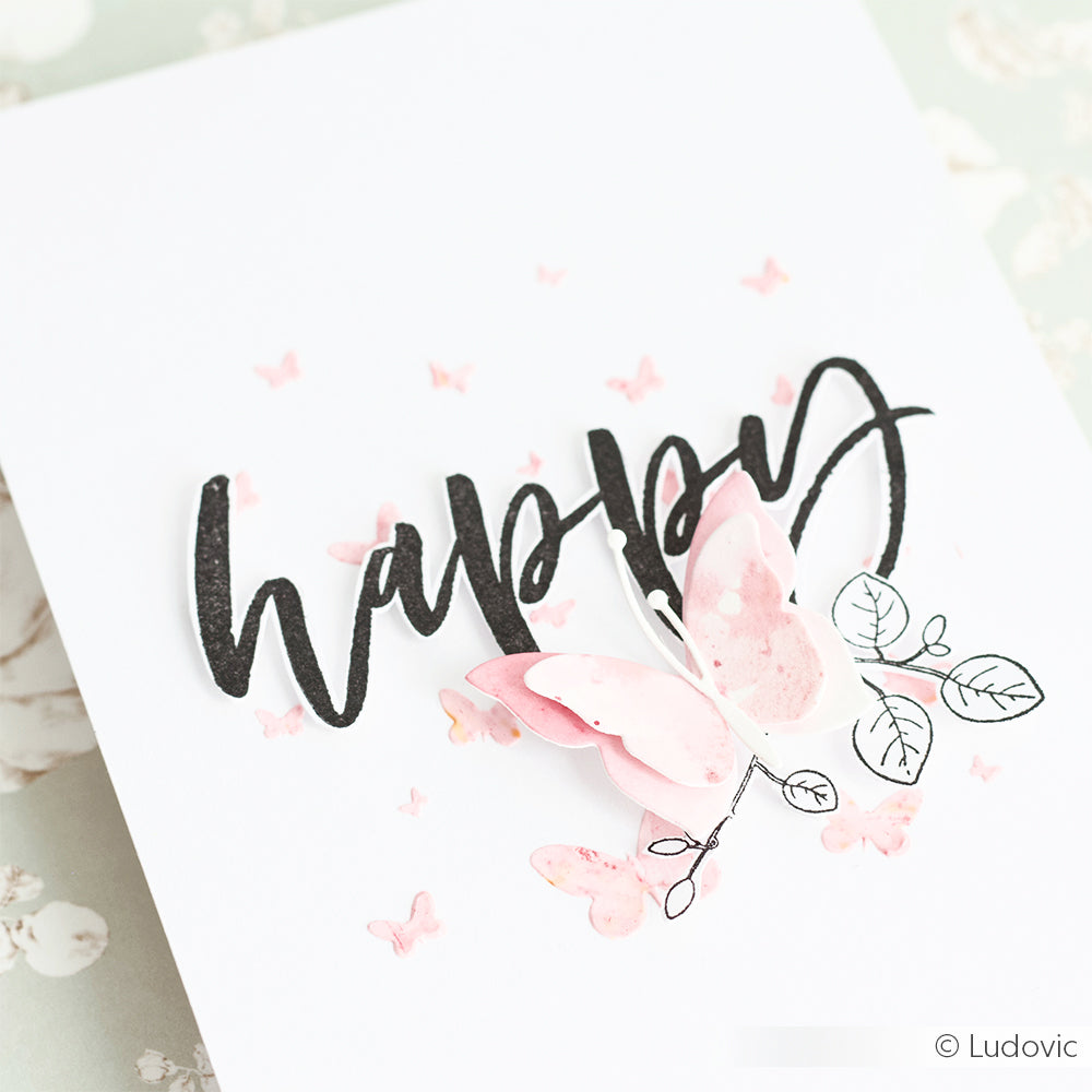 Eine weiße Karte von Alexandra Renke mit "happy" in schwarzer Schrift, rosa Schmetterlingen, einem Schmetterling mit skizzierten Blättern und Akzenten aus dem Stempelset Blumenzweige Merci Clear.