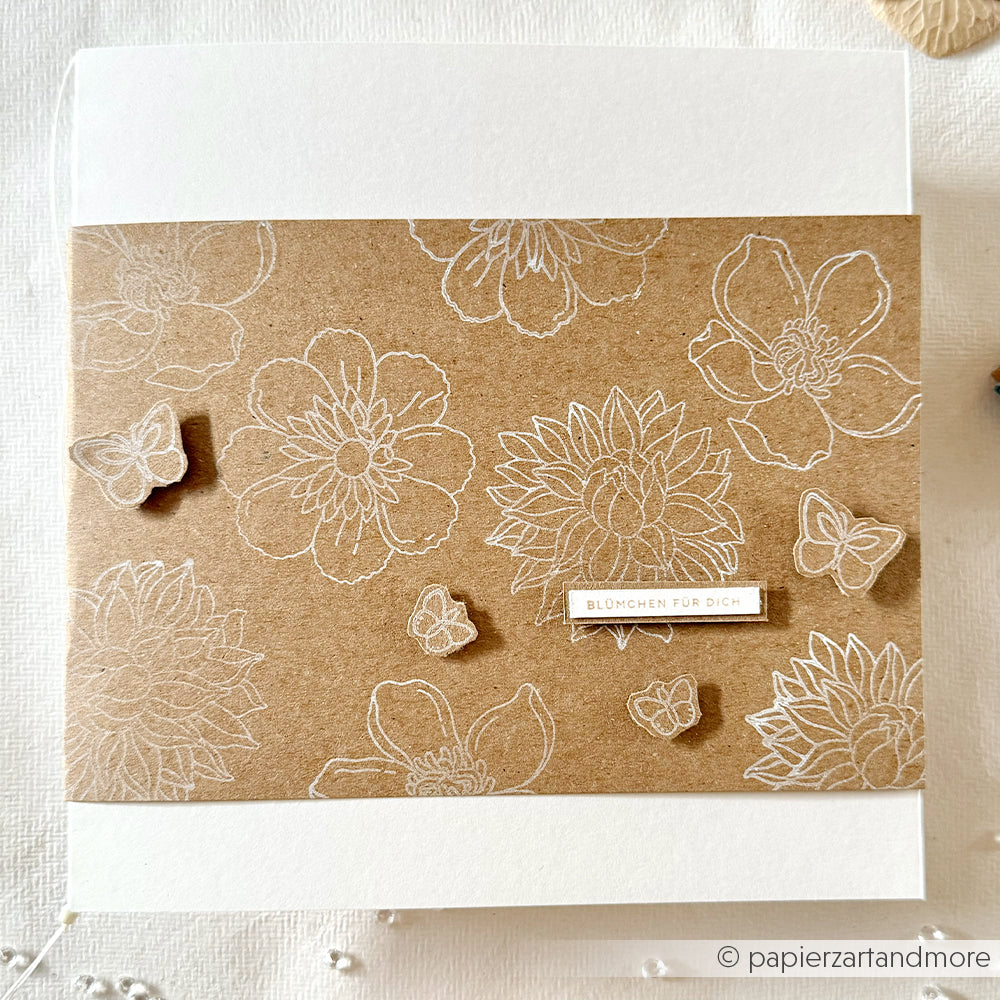 Braune Karte mit weißen Blumen- und Schmetterlingsstrichzeichnungen, gestaltet mit dem hochwertigen Fotopolymer-Stempelset „Sommerblüten“ von Alexandra Renke, sowie einem kleinen Etikett mit der Aufschrift „Blümchen für dich“.