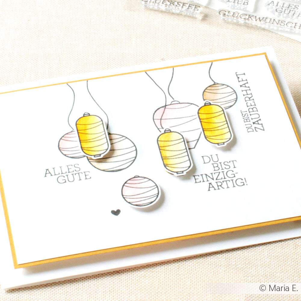 Handgefertigte Karte von Alexandra Renke mit gelben und weißen Papierlaternen, mit dem Text "ALLES GUTE" und "DU BIST EINZIGARTIG!" Gestempelt für ein knackiges Finish. Perfekt, um die besten Wünsche zu jedem deutschen Anlass zu übermitteln.