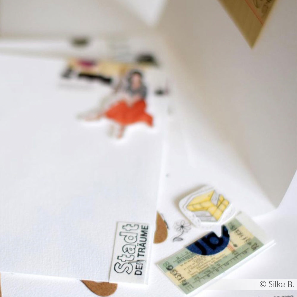 Alexandra Renke Sticker, Papierausschnitte und ein klares Stempelset sind auf einer weißen Fläche mit dem Text "Stadt der Träume" verstreut - ideal für kreative Papierprojekte.