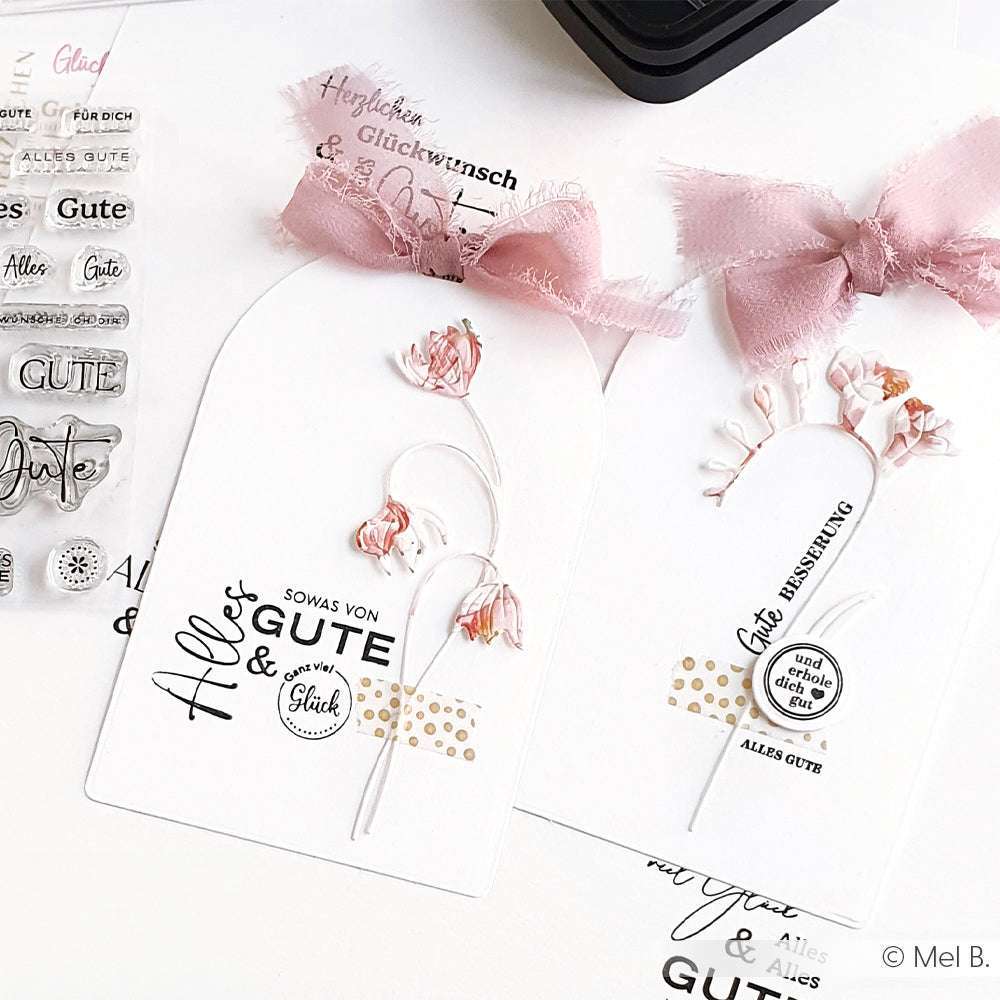 Zwei handgefertigte Geschenkanhänger von Alexandra Renke mit rosa Schleifen, getrockneten Blumen und dekorativem deutschen Text - perfekt, um jedem Geschenk eine besondere Note zu verleihen.