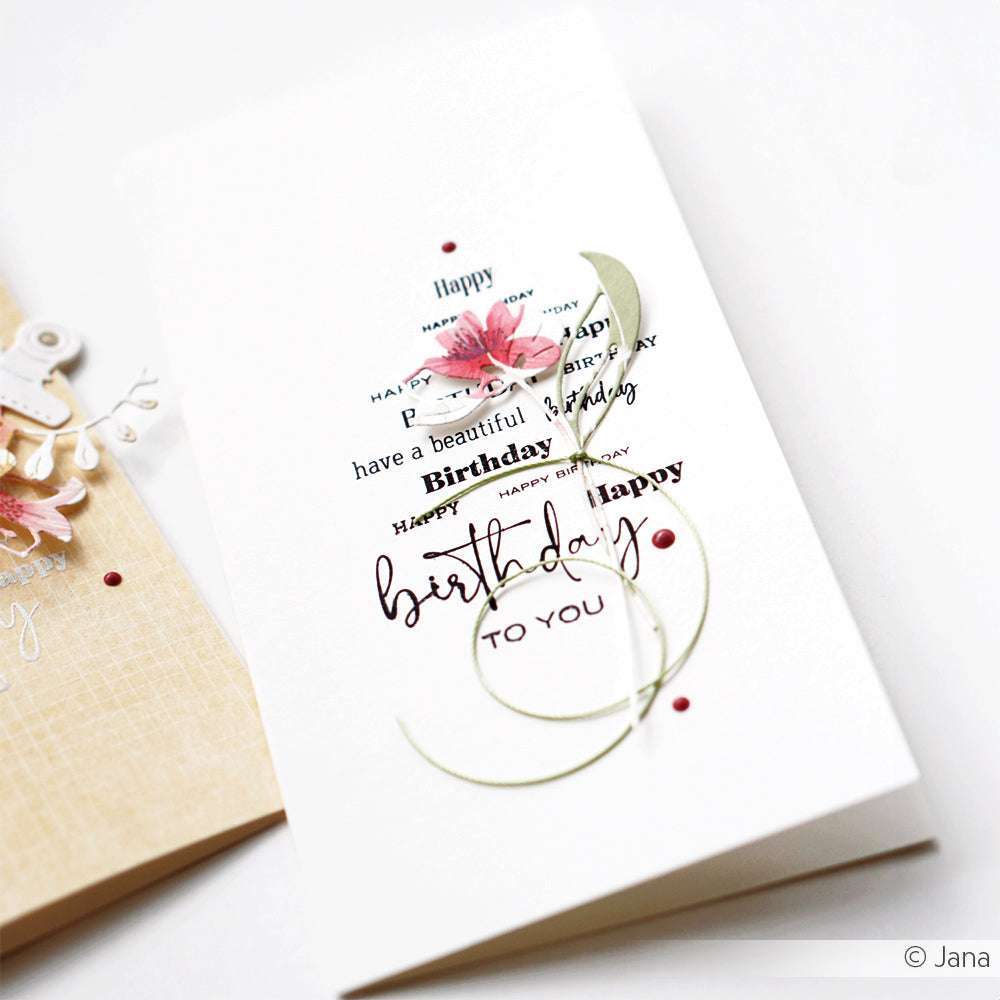 Eine weiße Geburtstagskarte von Alexandra Renke mit floralen Akzenten und einem überlagerten "Happy Birthday to you"-Text, der mit einem eleganten Happy-Birthday-Stempel-Design versehen ist.