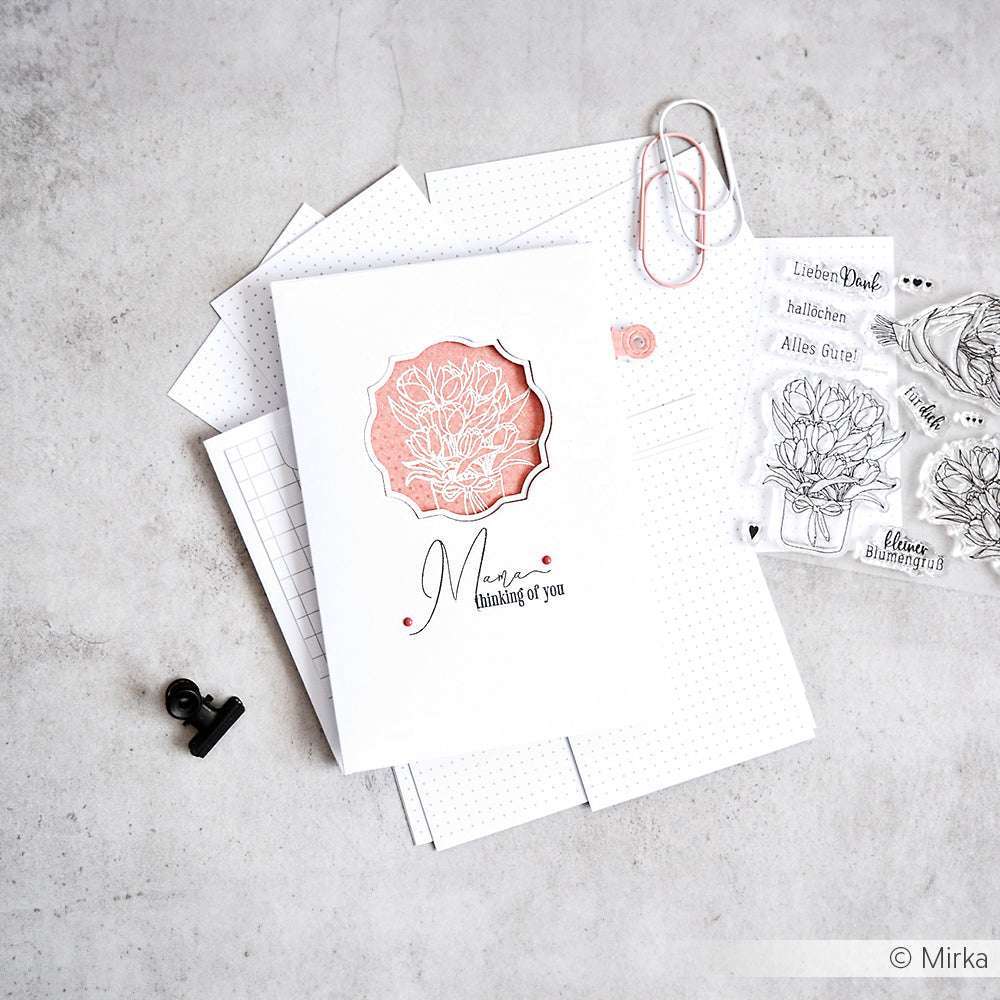 Eine handgefertigte Blumenkarte von Alexandra Renke, die von Briefpapier und klaren Stempeln umgeben ist - ideal, um Kreativität zu wecken oder um sie als Geschenk zu verpacken.