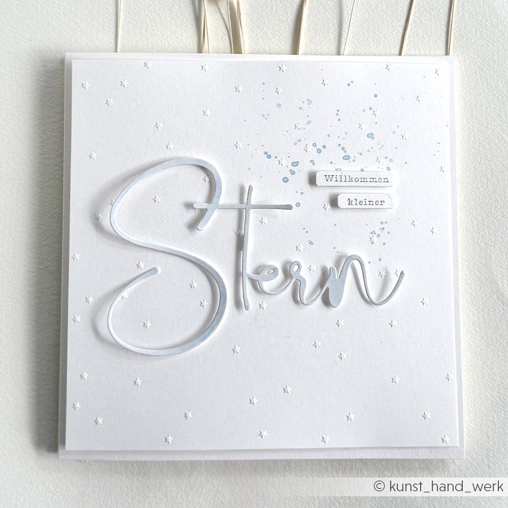 Die weiße Karte von Alexandra Renke zeigt geprägte Sterne, "Stern" in Schreibschrift und "Willkommen, kleiner" - perfekt, um mit Ihren Lieblingsmotiven aus Photopolymer oder Klarsichtstempeln zu verkünden: "It's a boy".