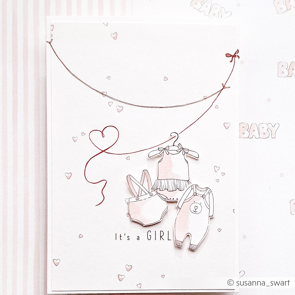 Eine Grußkarte von Alexandra Renke mit Babykleidung auf einer Leine, einem Herzballon und dem Text "It's a GIRL" - perfekt, um sie mit Ihren Lieblingsstempeln oder Photopolymer-Stempeln zum Thema Baby zu kombinieren!.