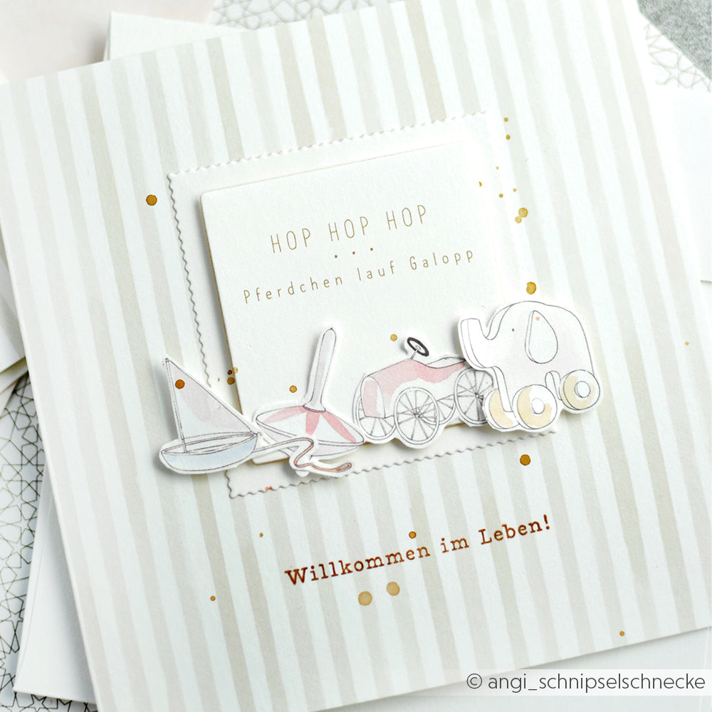 Alexandra Renke-Grußkarte mit Spielzeug-Illustrationen und dem Text "Willkommen im Leben!" auf gestreiftem Hintergrund - ideal für Papierprojekte oder zum Gestalten mit Ihren Lieblingsmotiven aus Photopolymer-Stempeln.