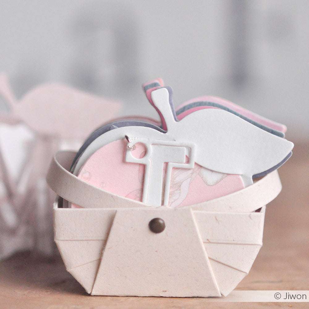 Kleines beigefarbenes Papierkörbchen von Alexandra Renke, das pastellfarbene Apfelausschnitte mit weißem T enthält - perfekt gestaltet mit den Motivstanze Picknickkorb Dies.