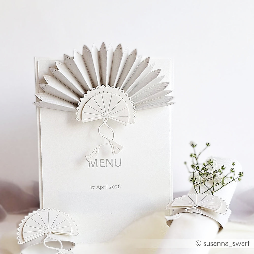 Elegante weiße Menükarte mit einer fächerförmigen Papierdekoration aus Alexandra Renke Motivstanze Faltfächer, daneben zarte Schleierkrautblüten, alles schön arrangiert auf hochwertigen Alexandra Renke Designpapieren.