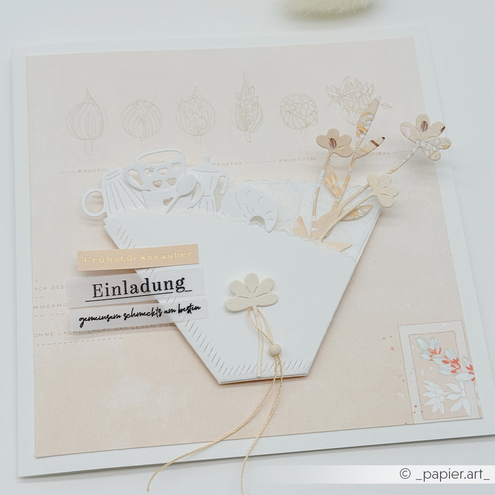Elegante, handgefertigte Karte mit floralen Motiven, die mit der Motivstanze „Kaffeefilter“ von Alexandra Renke gestaltet wurden, deutschem Text und einem weißen Umschlag auf hellem Hintergrund.
