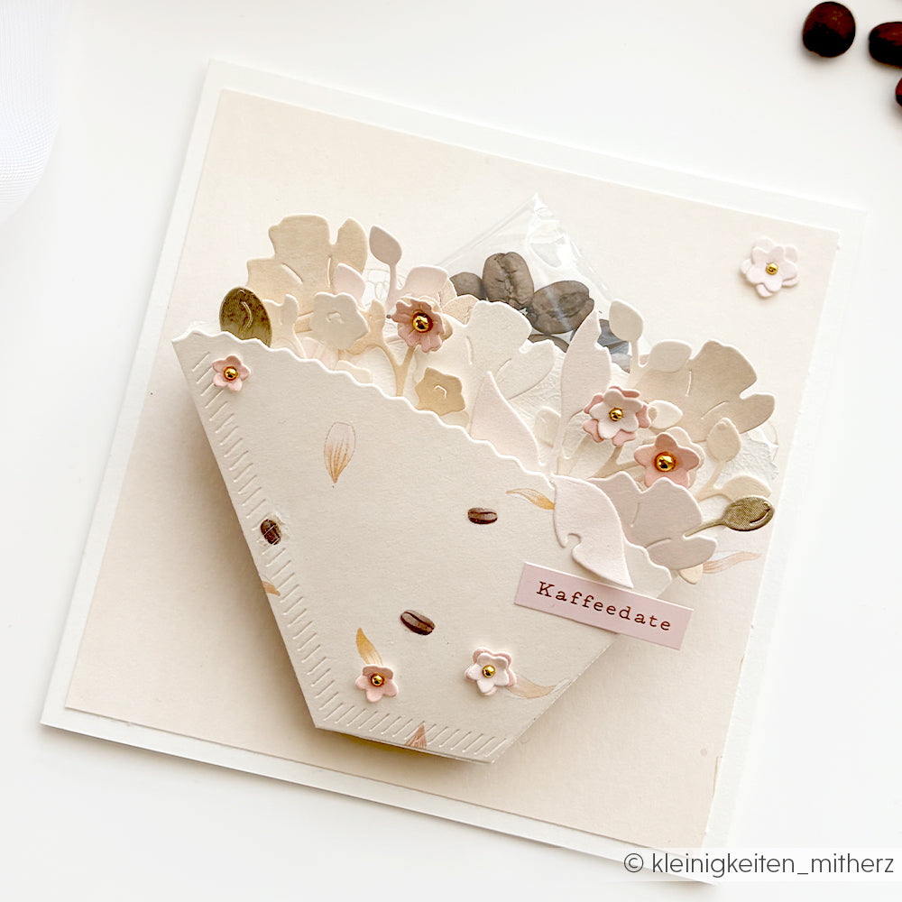 Handgefertigte Karte mit Blumenverzierungen, Kaffeebohnen und einem Etikett mit der Aufschrift „Kaffeedate“ auf cremefarbenem Hintergrund, gestaltet mit der Motivstanze „Kaffeefilter“ von Alexandra Renke und eleganten Designpapieren von Alexandra Renke für eine einzigartige Note.
