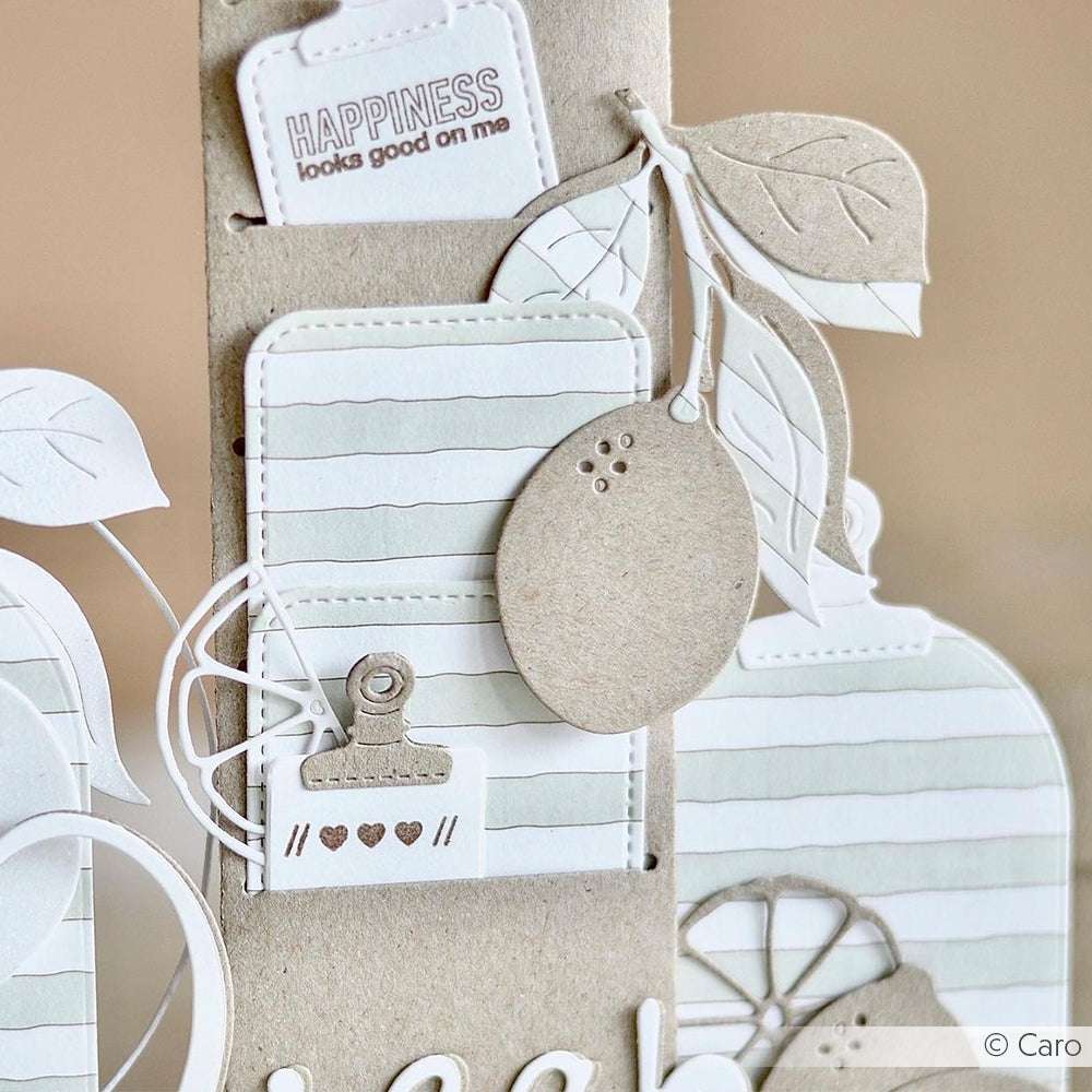 Handgeschöpftes Papierschild mit Blättern, einem Zitronenausschnitt und der Aufschrift "HAPPINESS looks good on me", hergestellt mit Alexandra Renke Stanzen für Papier für präzise Details.