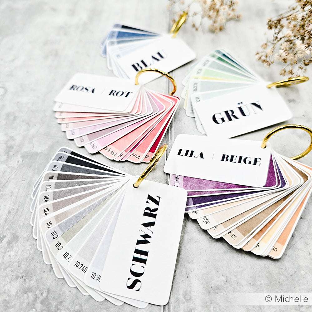 Fächerförmige Farbmusterkarten von Alexandra Renke, beschriftet für verschiedene Farbgruppen, auf einer hellen Fläche - perfekt für Designpapiere und DieCut Systeme.