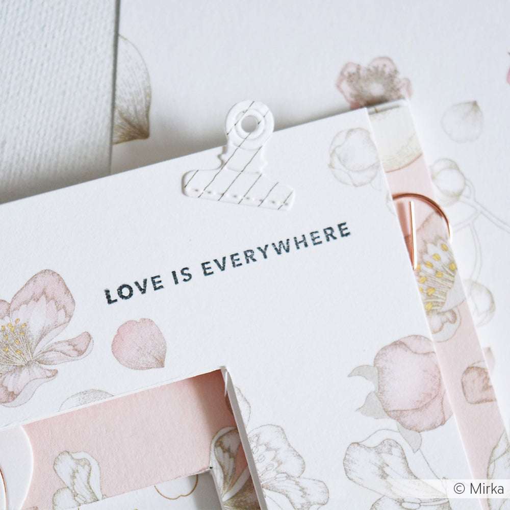 Eine Blumenkarte von Alexandra Renke mit "LOVE IS EVERYWHERE" in Schwarz, verziert mit pastellfarbenen Blumen und zarten Rändern, die mit Stanzsystemen hergestellt wurden.