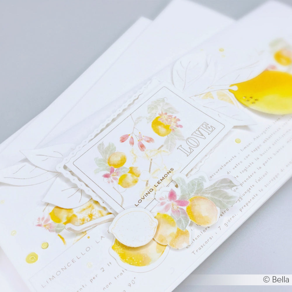 Eine Nahaufnahme einer weißen Alexandra Renke Hochzeitseinladung, verziert mit gelben Zitronen, floralen Illustrationen, dem Wort LOVE, und veredelt mit einer zarten Motivstanze Wellenrahmen auf hochwertigen Designpapieren.