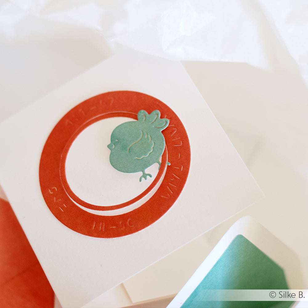 Die Karte von Alexandra Renke zeigt einen roten Kreis und einen blaugrünen Granatapfel auf weißem Designpapier, das mit dem DieCut System für Präzision hergestellt wurde.