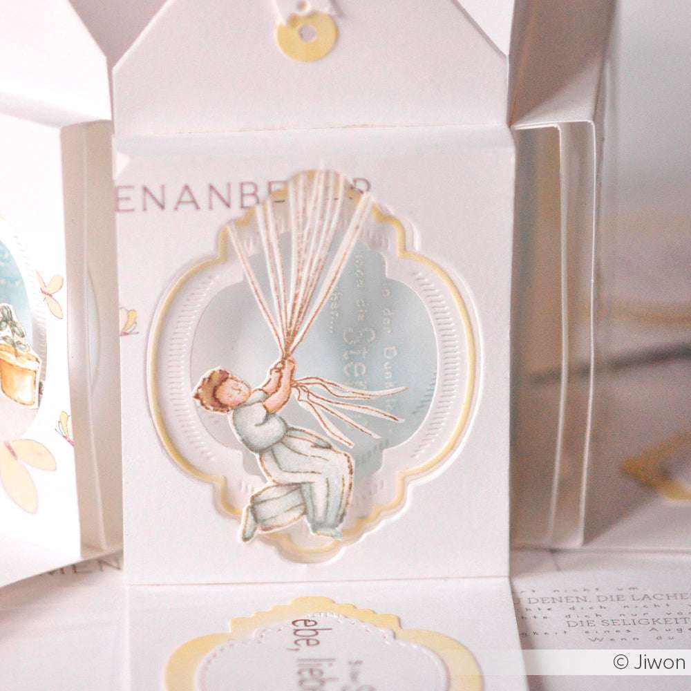 Illustration eines Kindes, das Luftballonschnüre in der Hand hält, eingerahmt von übereinanderliegenden weißen und gelben Papierausschnitten, die mit Alexandra Renke DieCut Systemen für zusätzliche Dimension und kreativen Charme akzentuiert wurden.