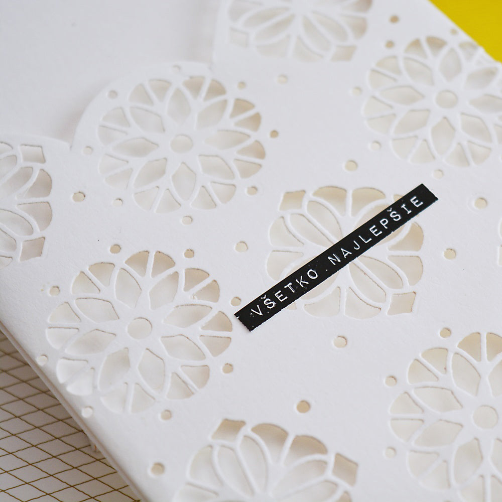 Weiße Karte mit floralen Ausschnitten, hergestellt mit Alexandra Renke Stanzsysteme und Designpapiere, mit einem schwarzen Etikett mit der Aufschrift "Všetko najlepšie" auf Slowakisch.