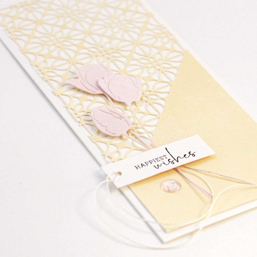 Handgefertigte Karte mit pastellfarbenen Blumen, Spitzenausschnitt mit Alexandra Renke Motivstanze Ornament mit Kontur und einem Etikett auf der Vorderseite mit der Aufschrift "Glückliche Wünsche".