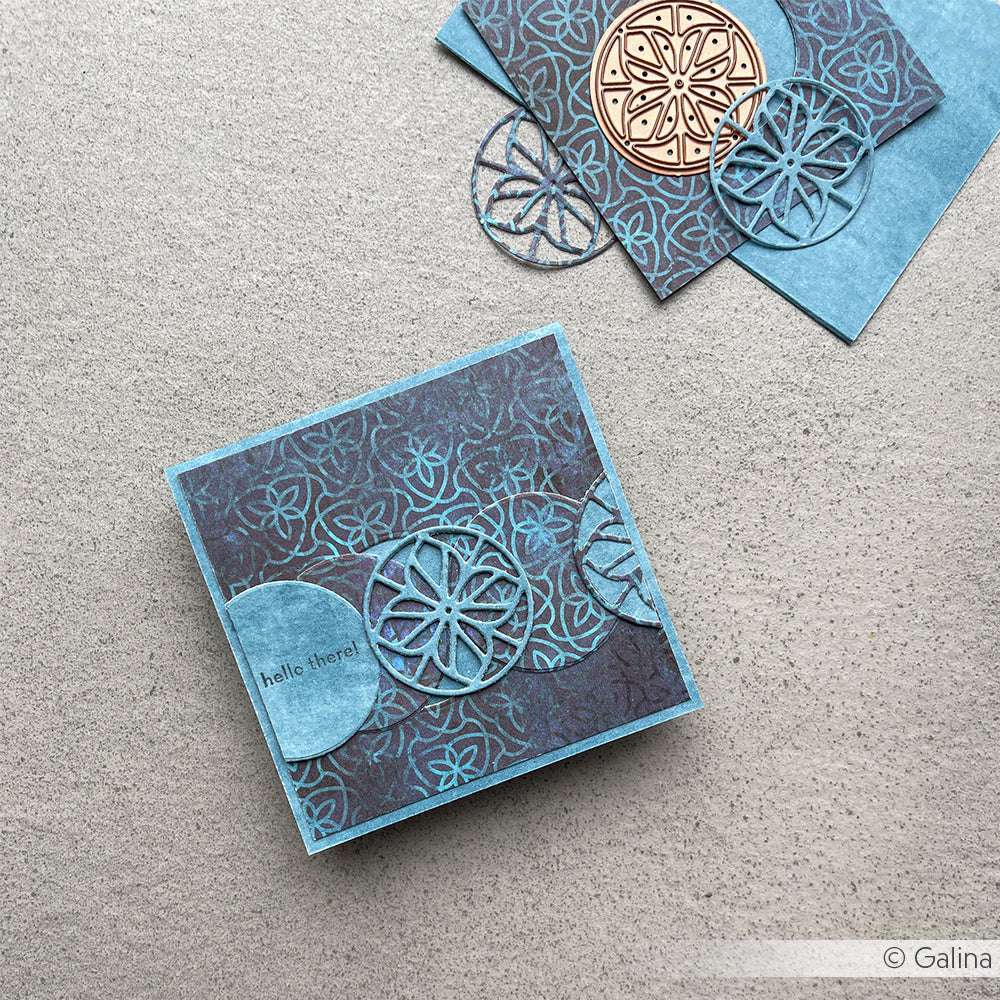 Blaue und kupferfarbene Blumengrußkarten mit runden Ausschnitten, hergestellt mit dem Alexandra Renke Motivstanze Ornament DieCut Systeme, auf einer strukturierten grauen Oberfläche.