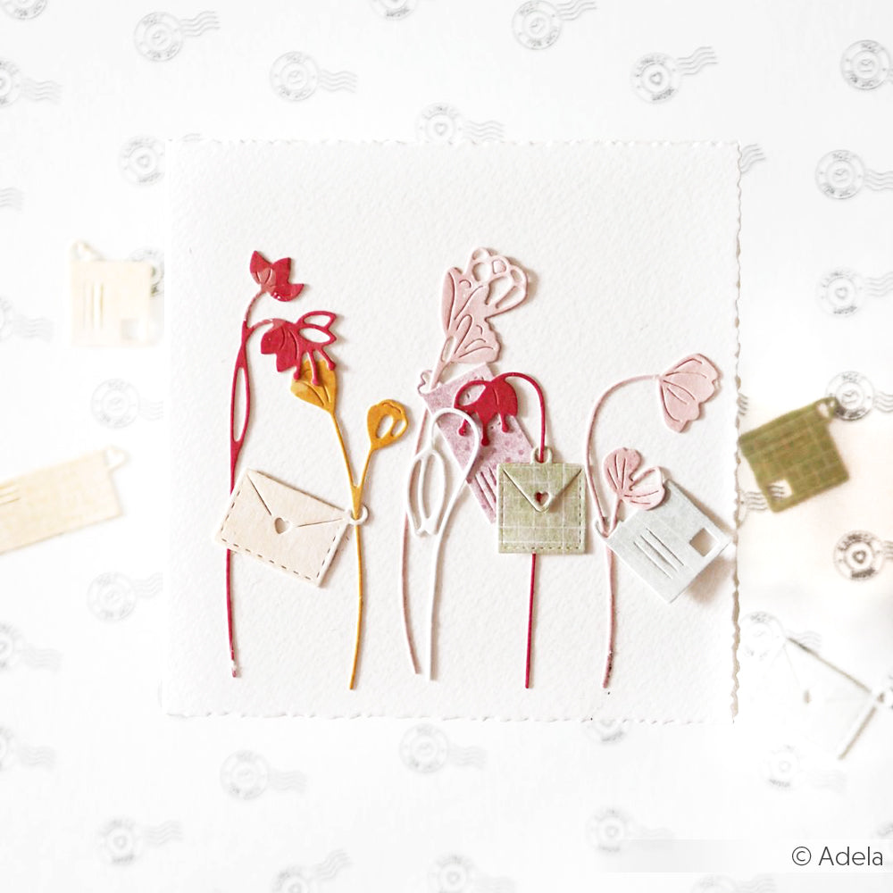 Papierblumen mit Blättern in Form eines Briefumschlags zieren eine weiße quadratische Karte, die mit den Alexandra Renke Stanzformen für Paper Crafting vor einem charmanten Hintergrund mit Postmotiv gestaltet wurde.