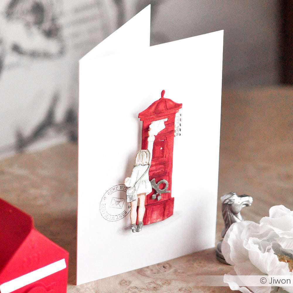 Eine bezaubernde Grußkarte von Alexandra Renke, die ein Mädchen zeigt, das einen Brief in einen roten Briefkasten mit einer weißen Blume steckt - ideal für Ihr Brieffreundin-Set oder in Kombination mit Ihren Lieblingsmotivstanze-Motiven.